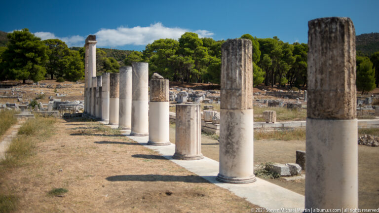 Perspective along restored stone columns, with a large weathered shaft in front and smaller reconstructed columns receding behind.