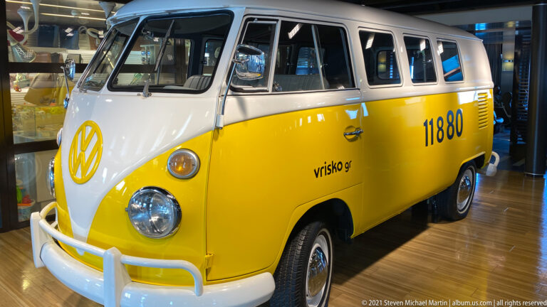Yellow-and-white vintage Volkswagen minibus displayed indoors, with split windshield, round headlights, white bumpers, and black 11880 numbering.