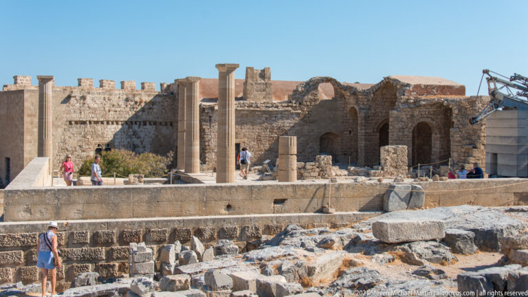 Standing columns, stone foundations and terraces fill the interior of Lindos Acropolis beneath the fortified wall.