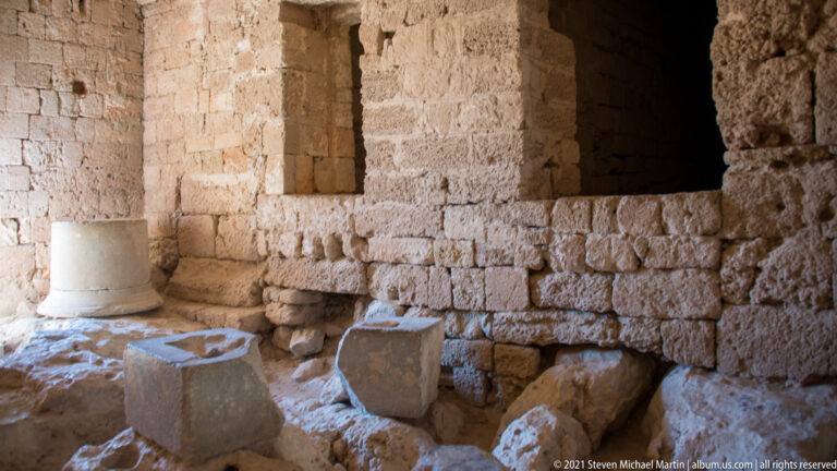 Dim stone chamber with a rectangular opening and several carved architectural blocks resting on the floor.