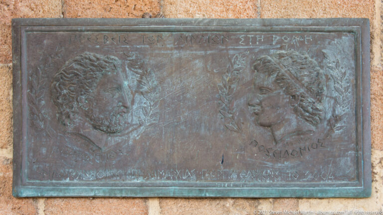 Bronze plaque with two facing profile portraits, Greek inscriptions and decorative branches mounted on stone.