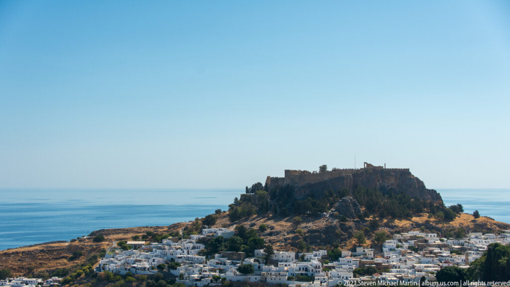 Fortified Lindos Acropolis rises above the whitewashed village with the blue Aegean Sea stretching behind.