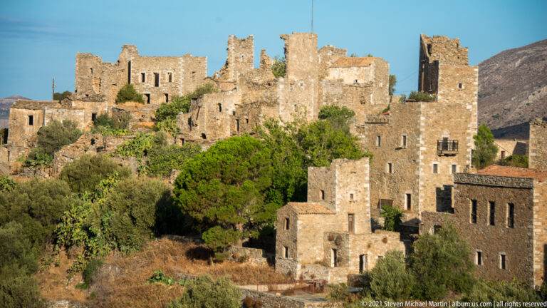 Dense cluster of tall weathered stone towers and houses rising among green trees.