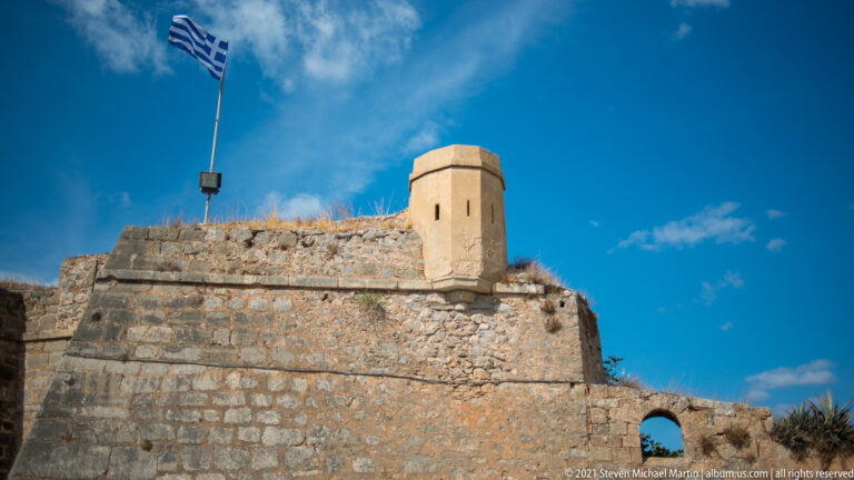 Small projecting stone lookout with narrow openings above the heavy masonry wall of Palamidi Fortress.