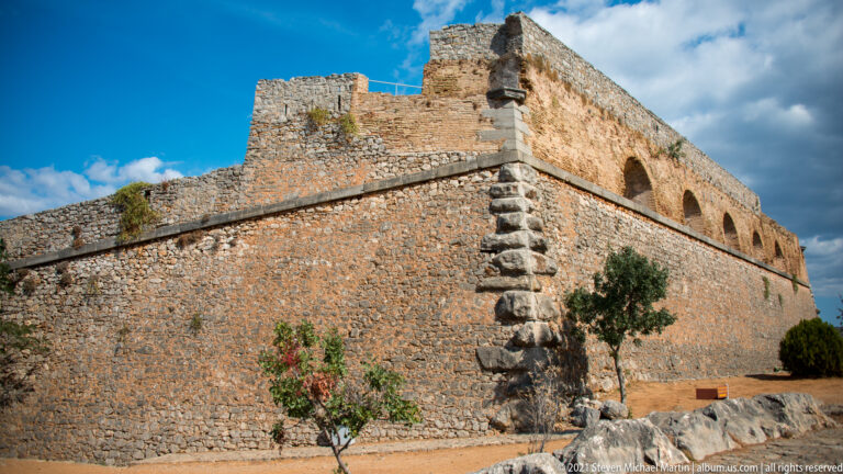 Massive angular Palamidi bastion with dressed corner stones and broad arched openings along the upper level.