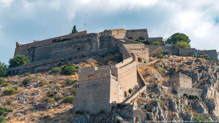 Close view of Palamidi’s stone ramparts zigzagging up a rugged limestone slope toward the summit fortifications.