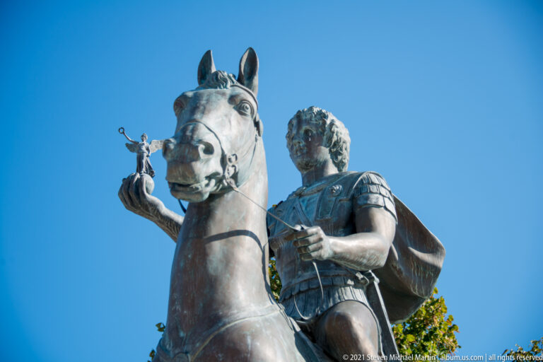 Low-angle view of Alexander the Great on horseback holding a small winged Nike on his outstretched hand.