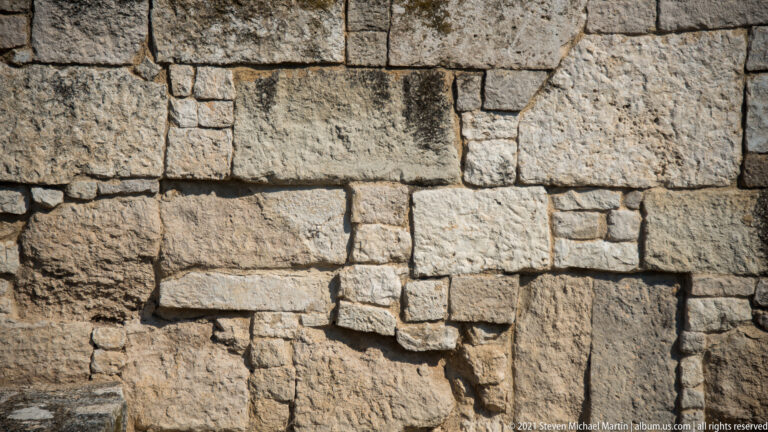 Close view of ancient stone wall built from large rectangular blocks with smaller infill pieces.