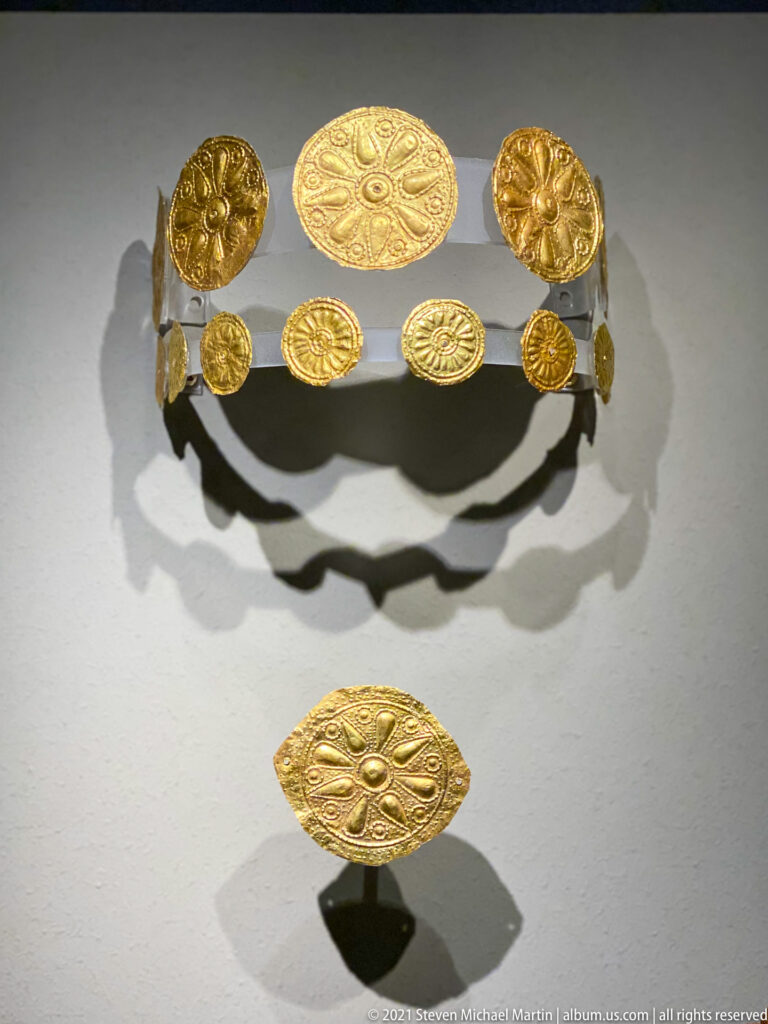 Embossed gold rosettes and circular plaques mounted as an ornament set, with a larger oval plaque below.