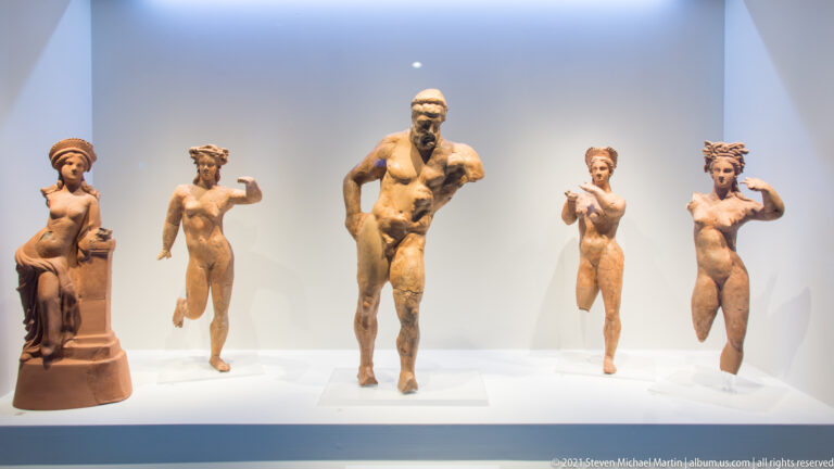 Five terracotta human figurines in varied poses, including a seated woman and a larger standing male figure.