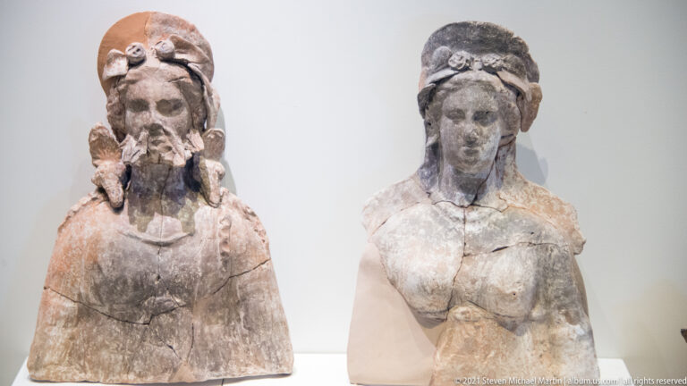 Two ancient female busts with elaborate headdresses and surviving traces of painted surface.