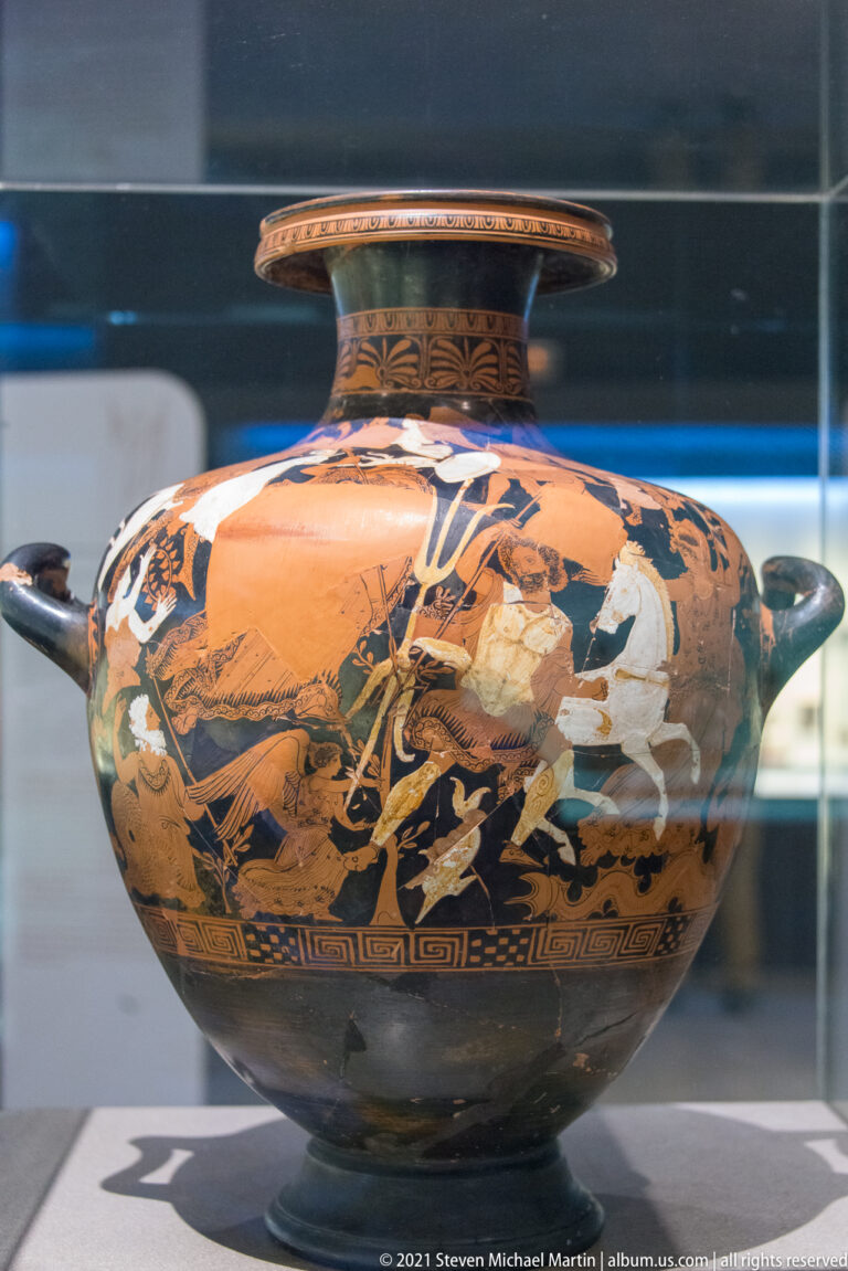 Large red-figure hydria with multiple human figures and horses painted across its dark glazed body.