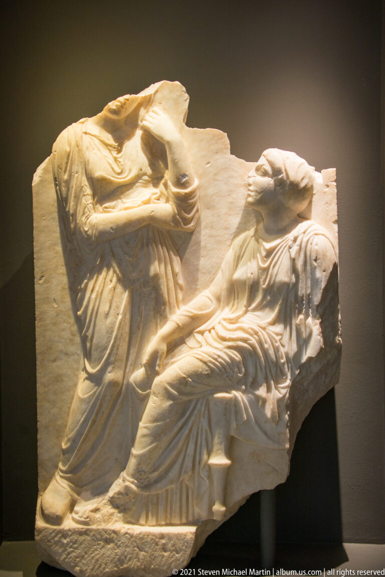 Fragmentary marble relief with two overlapping draped human figures and deeply carved folds.