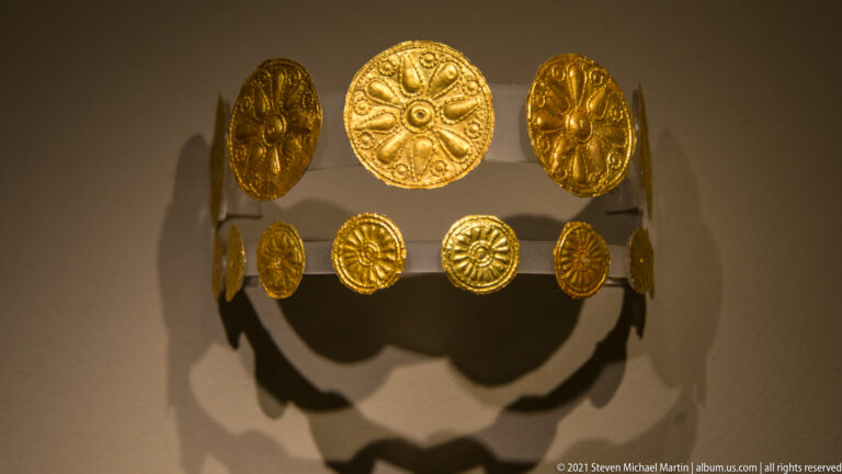 Close view of a gold band made from embossed circular rosettes of different sizes.