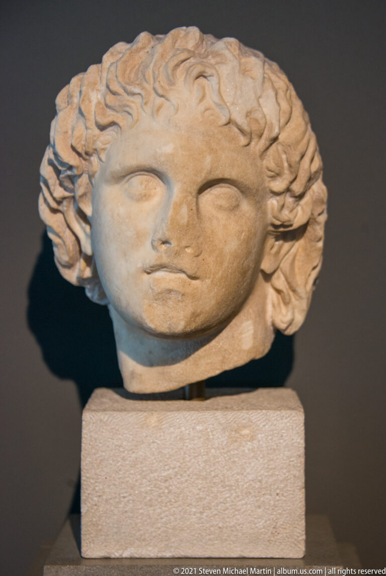 Marble portrait head associated with Alexander the Great, with youthful features and thick upswept wavy hair.