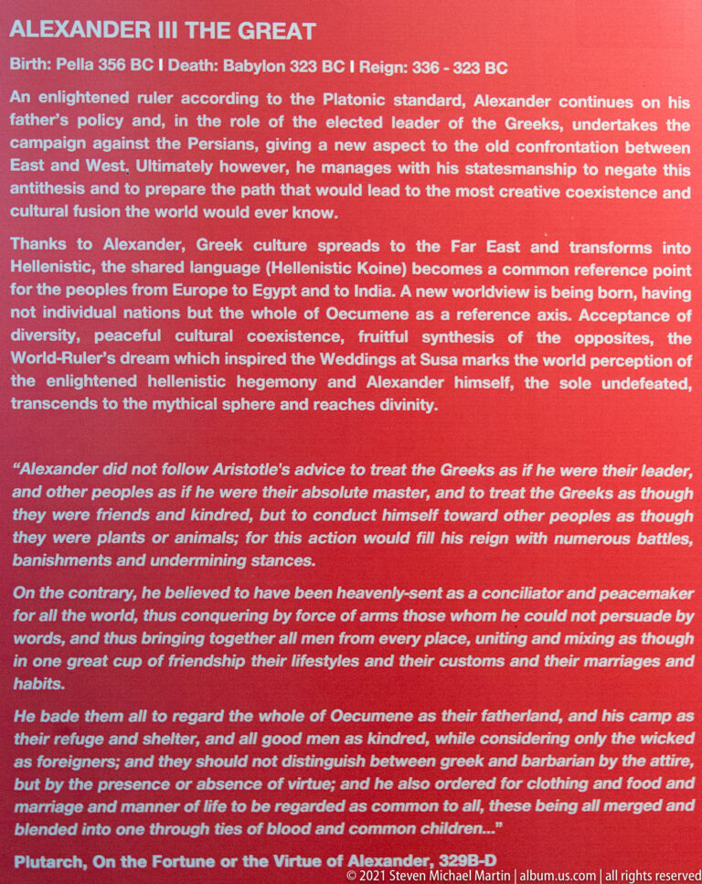 Red museum interpretive panel headed “Alexander III the Great,” filled with English text about his reign and conquests.