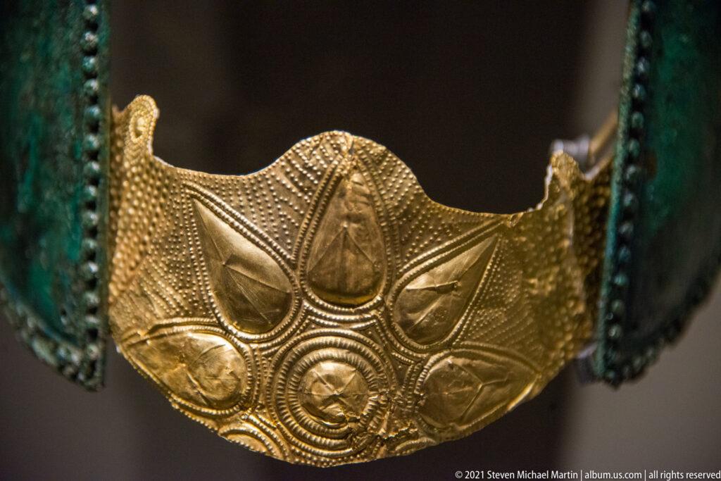 Embossed gold plaque with raised teardrop motifs, circular bosses, and dense punched-dot decoration.