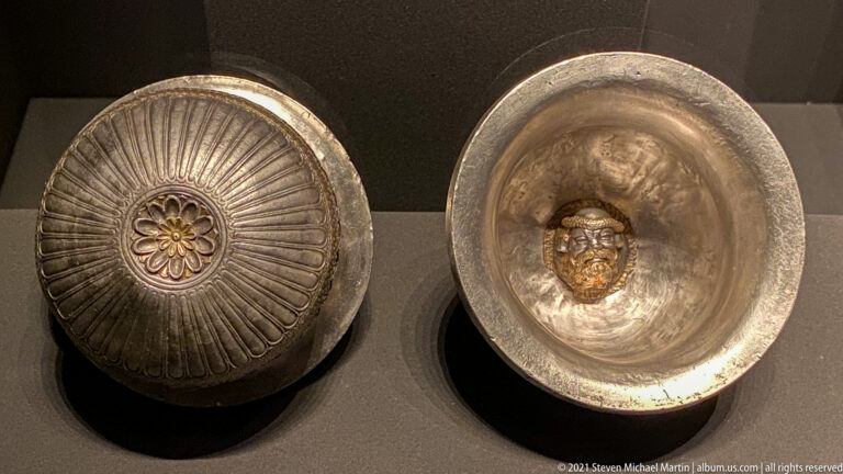 Two silver bowls side by side, one showing an exterior rosette with radial fluting and the other an interior face medallion.