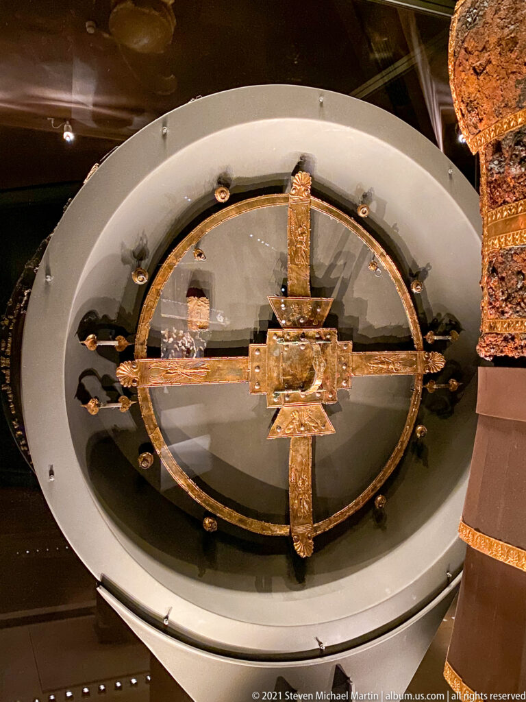 Large circular frame with four cross-braces, a square central fitting, and small metal attachments around the rim.