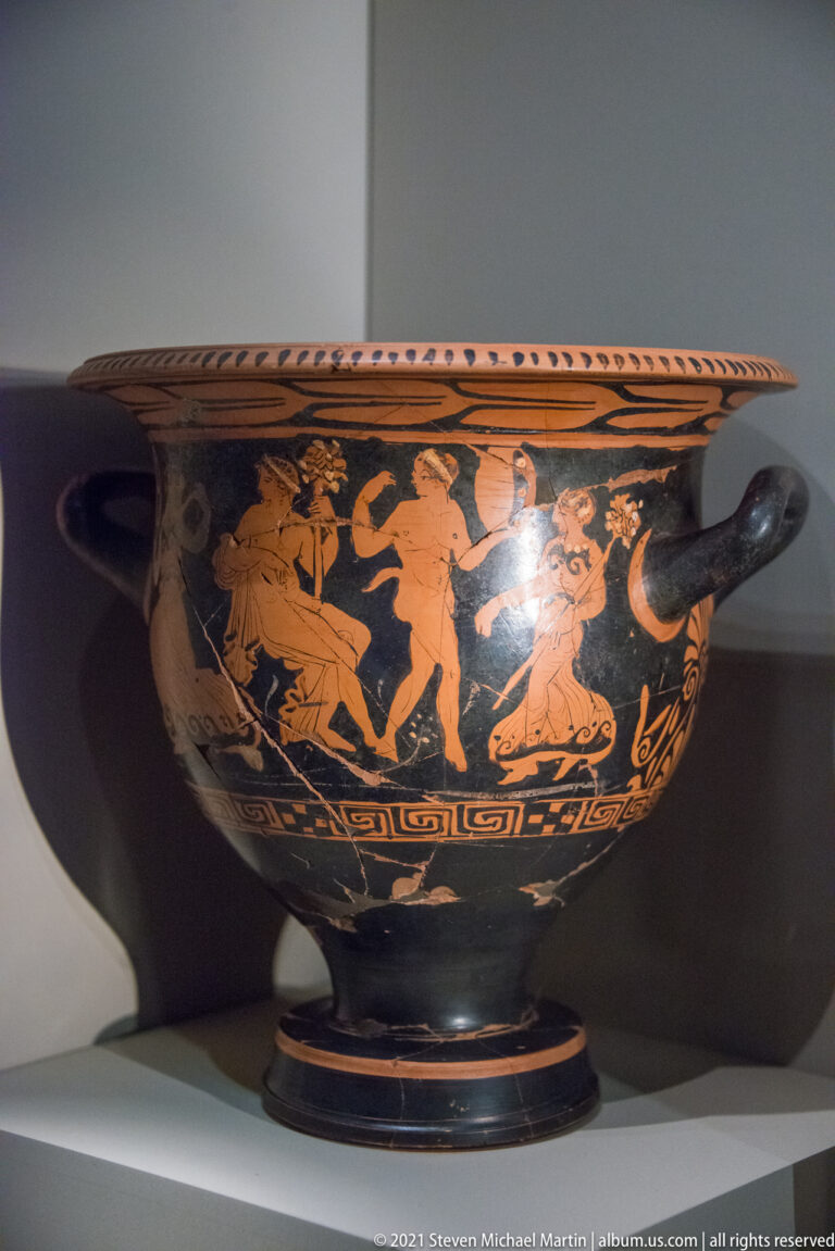 Wide black two-handled red-figure vessel with an orange multi-figure scene extending around the body.