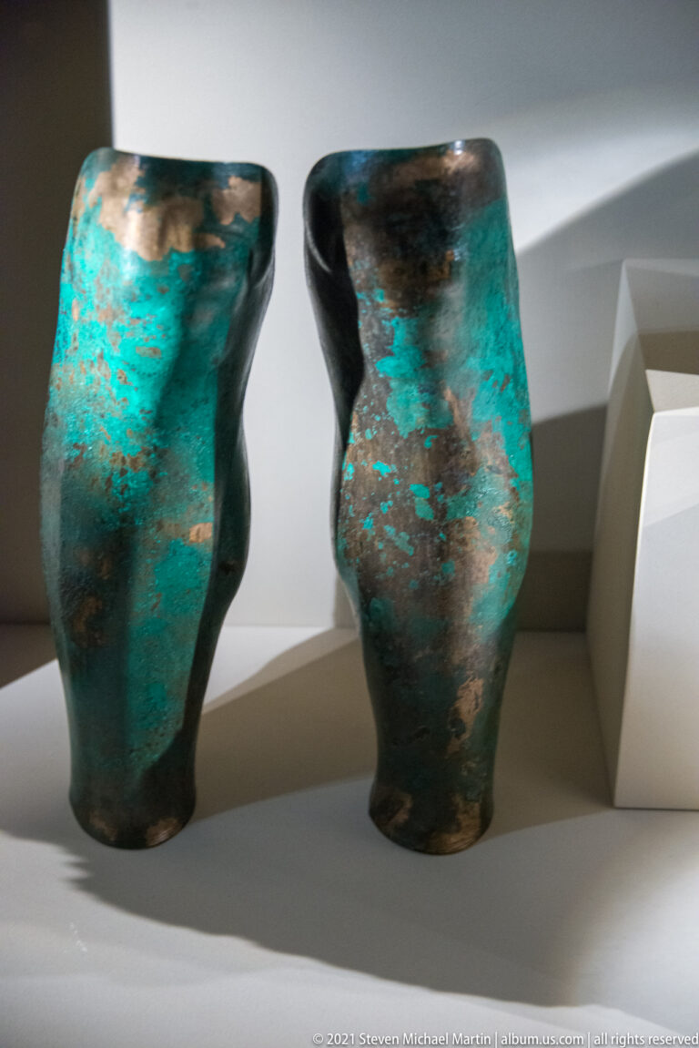 Two small footed bronze vessels with rounded bodies and mottled turquoise-green patina displayed side by side.