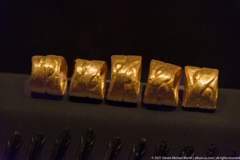 Five embossed gold armor fittings from the Tomb of Philip II, each decorated with raised figural and ornamental panels.