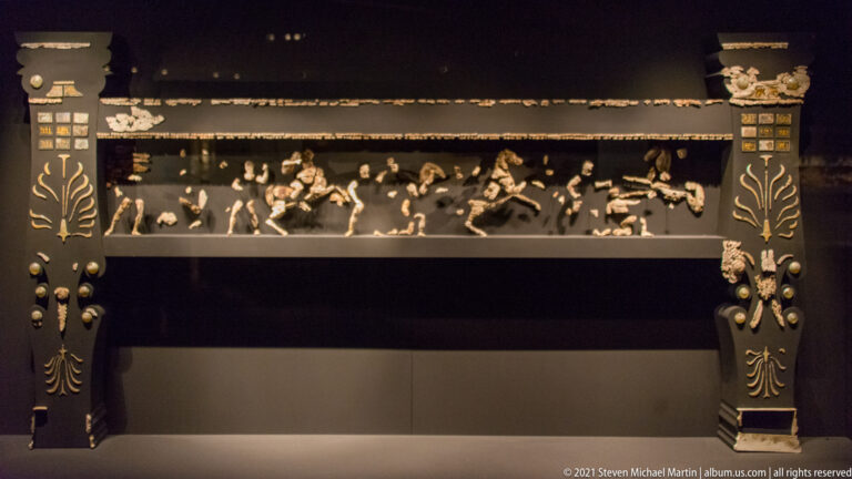 Reconstructed funerary couch from the Tomb of Philip II with surviving ivory figures and gilded decorative elements.