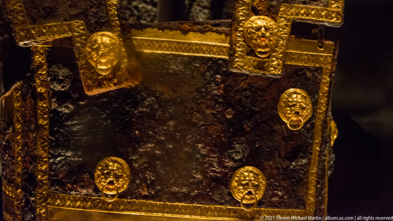 Dark furniture surface edged with gold bands and decorated by several round lion-head fittings with hanging rings.