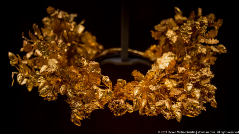 Close view of Philip II’s gold oak wreath with overlapping hammered leaves, acorns, blossoms, and fine stems.
