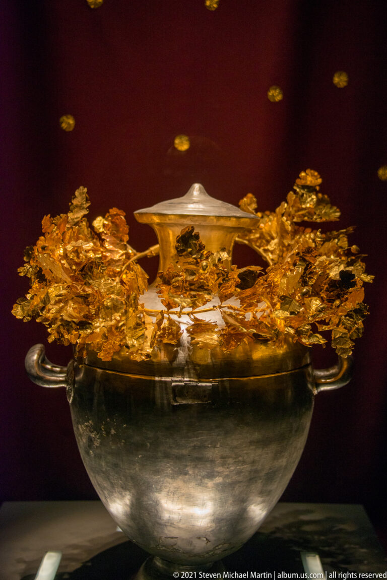 Large lidded silver hydria from the Prince’s Tomb displayed with a delicate gold botanical wreath around its upper body.