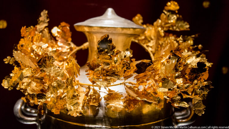 Silver hydria from the Prince’s Tomb rising from a dense gold funerary wreath of hammered leaves and stems.