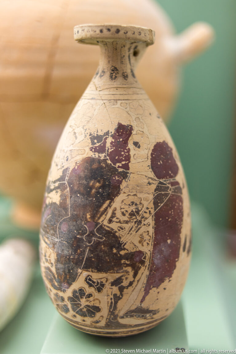 Small round-bodied ceramic flask with a broad disc-like rim and a large painted human figure on the body.