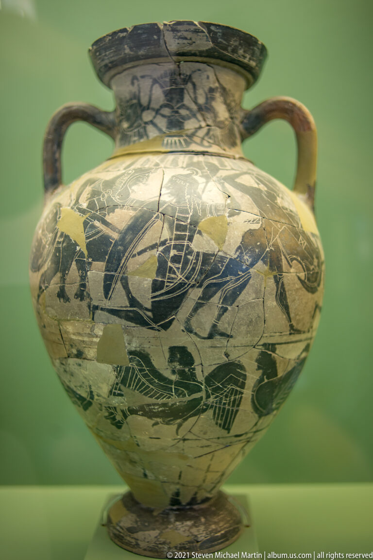 Large multi-handled ceramic jar with a dense black-figure scene and extensive losses to the painted surface.