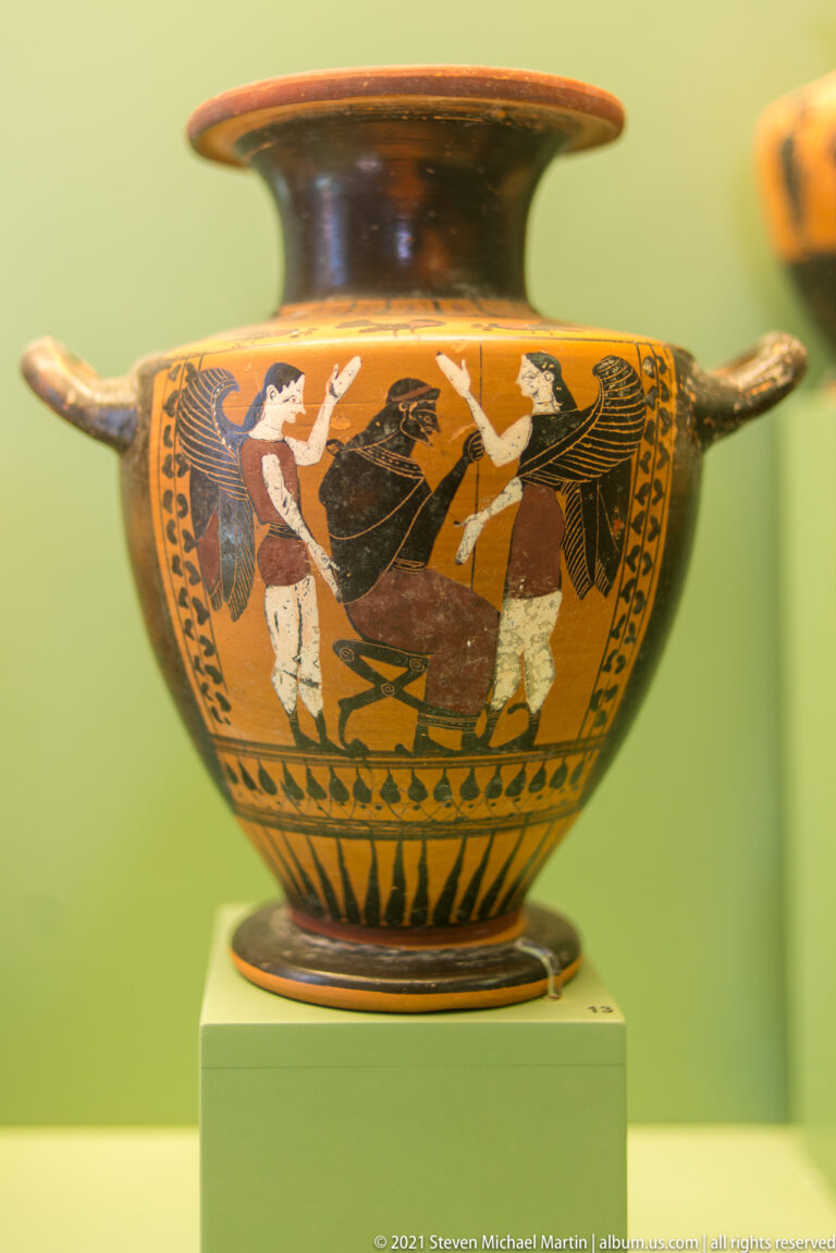 Two-handled ceramic vessel with large black-figure human forms, added red and white details, and a flaring rim.