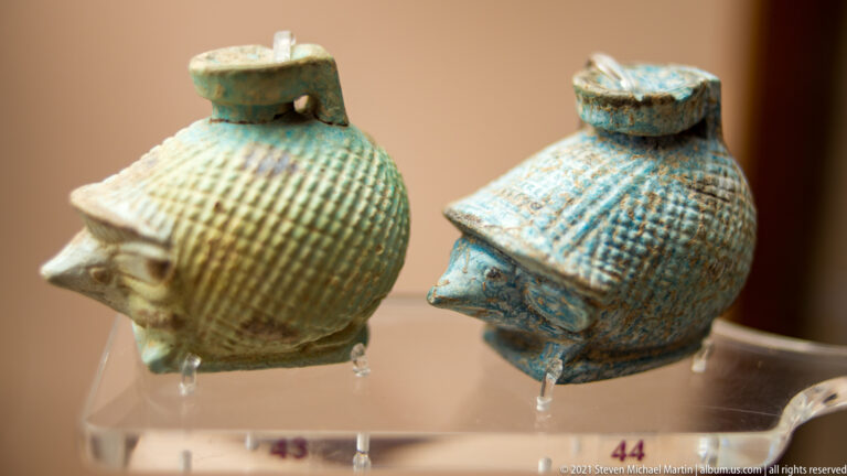 Two small turquoise-glazed shell-shaped objects with ribbed surfaces, pointed projections, and small top openings.