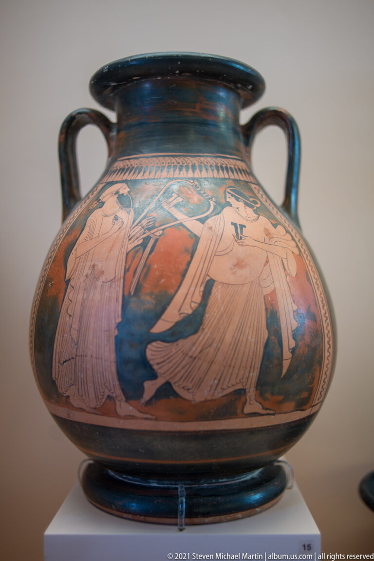 Large two-handled red-figure ceramic vessel decorated with several draped human figures against a black ground.