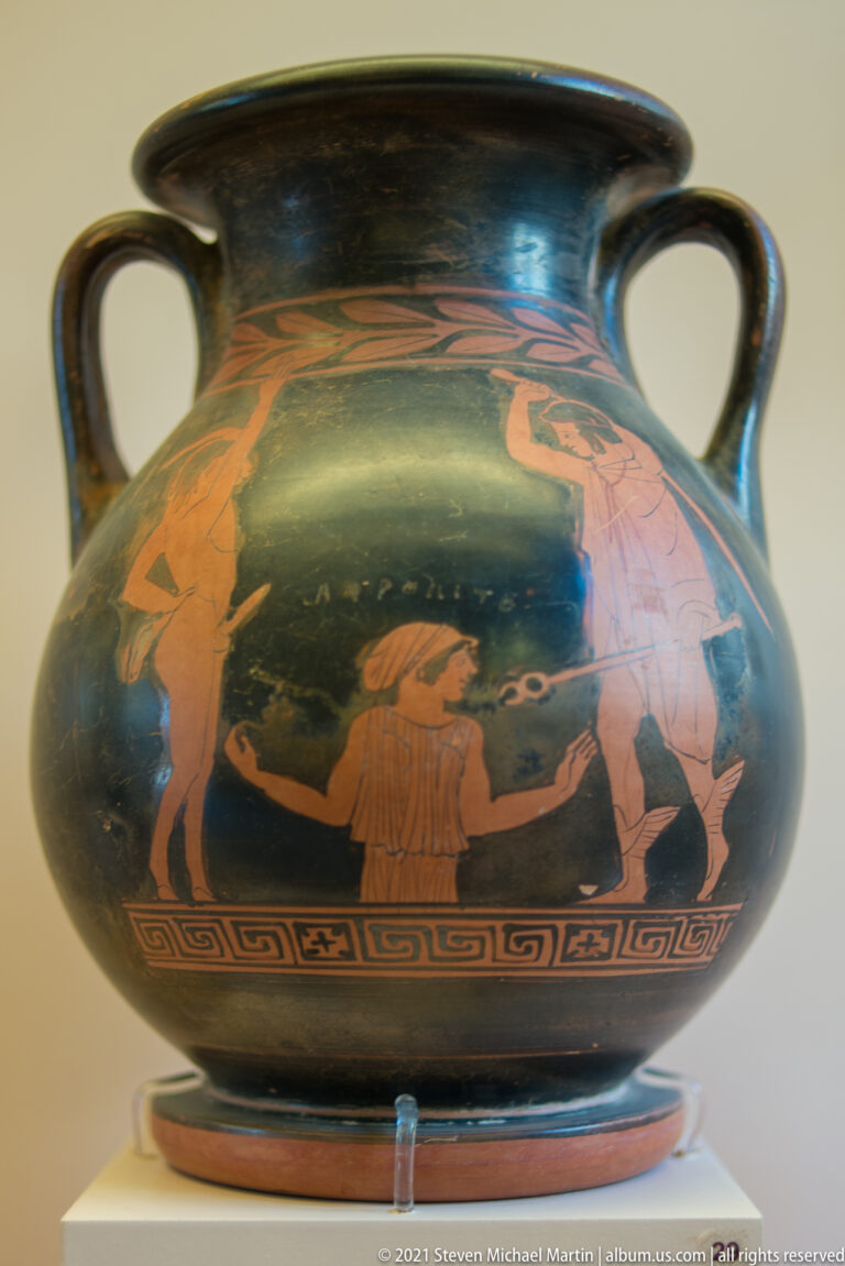 Two-handled red-figure vessel with reclining and standing human figures above a geometric border.