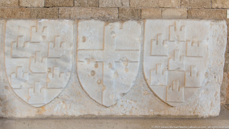 Rectangular stone panel carved with three adjacent shields bearing different geometric heraldic devices.