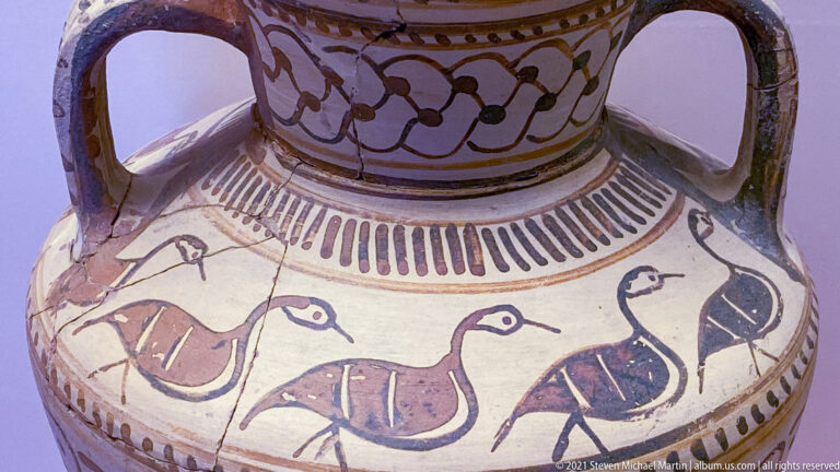 Painted ceramic shoulder with a row of long-necked birds in dark and reddish tones beneath geometric bands.