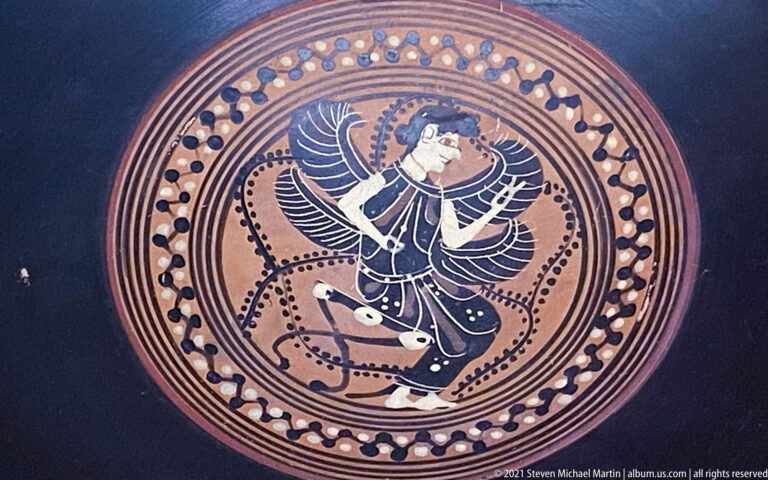 Circular painted ceramic medallion with a dynamic winged human figure surrounded by dotted and concentric bands.