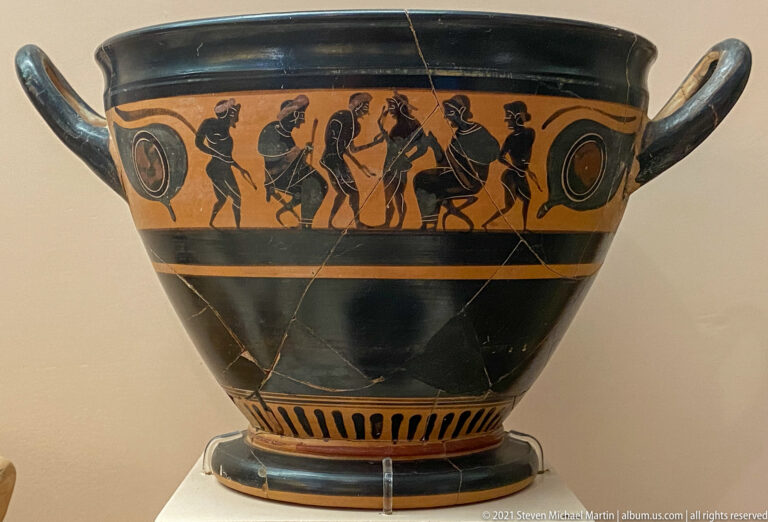 Large two-handled black-figure vessel with standing and seated figures in a narrow frieze beneath the rim.