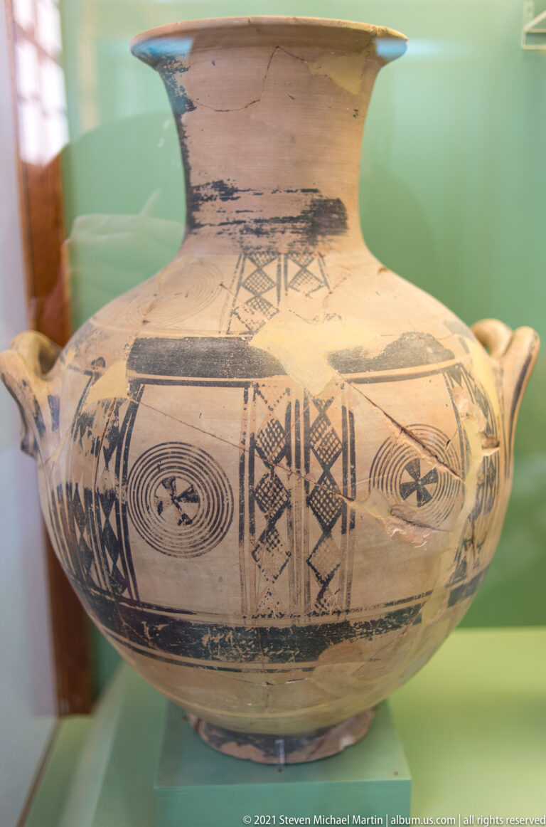 Two-handled pale ceramic vessel decorated with concentric circles, cross-hatched panels, and dark geometric bands.