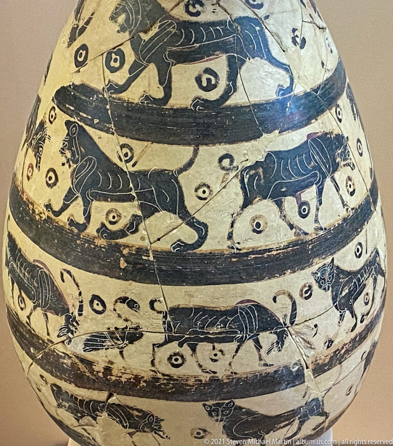 Pale ceramic vessel covered with horizontal friezes of dark animals, birds, and dotted filler motifs.