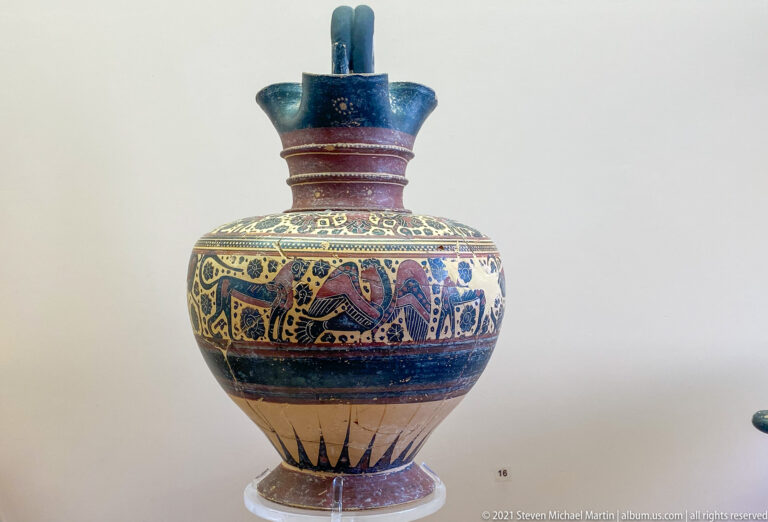 Rounded polychrome ceramic vessel with tall neck, animal frieze, and multiple geometric decorative bands.