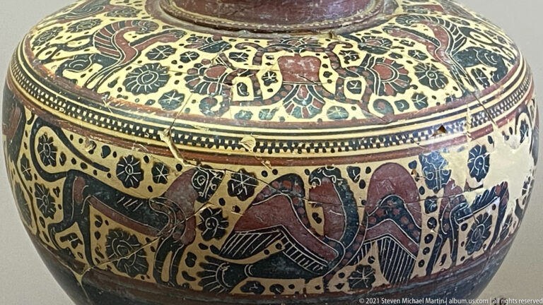 Polychrome ceramic vessel detail with large birds, quadrupeds, rosettes, and dense floral ornament.
