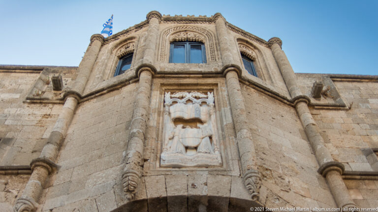 Projecting polygonal stone bay with traceried windows and a carved heraldic panel above a broad arch.