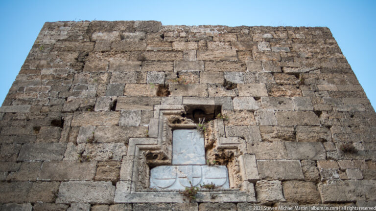 Weathered heraldic stone relief set into a massive wall of large rough-cut blocks.