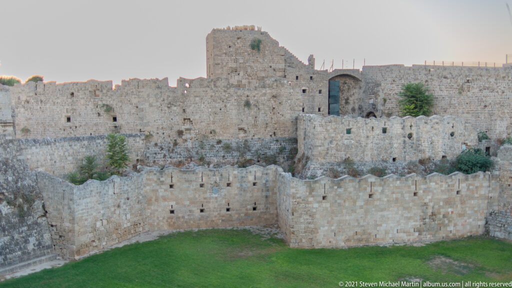 Multiple crenellated stone walls and a central tower enclosing green ground inside the fortifications.