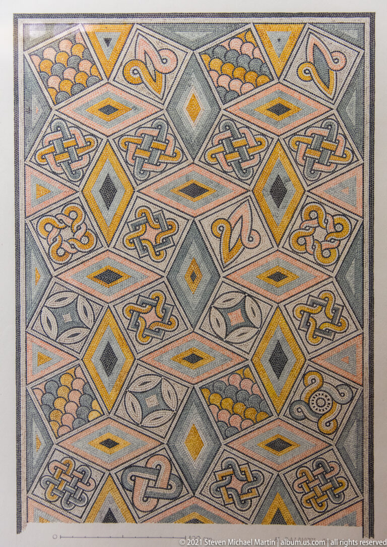 Polychrome mosaic filled with interlace knots, diamonds, stylized birds, fan motifs, and repeating gray, yellow, and orange geometry.