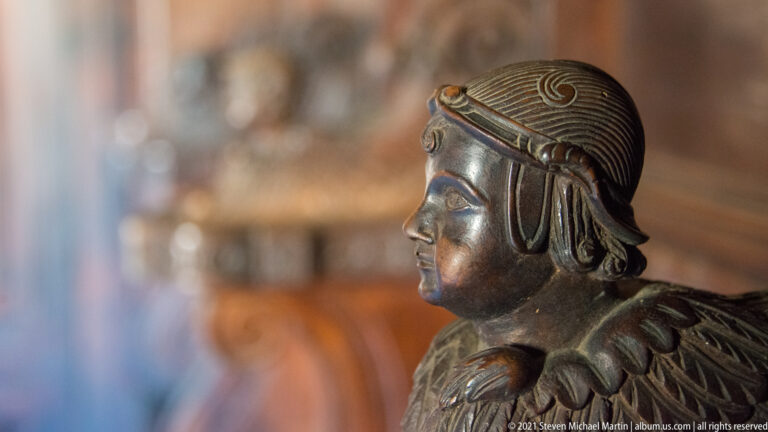 Close profile of a dark metal youthful head with stylized ridged hair, headband or cap, and smooth facial modeling.